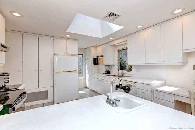 kitchen featuring freestanding refrigerator, a sink, light countertops, light tile patterned floors, and recessed lighting