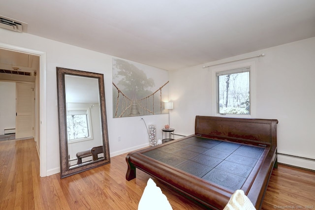 bedroom featuring wood finished floors, a baseboard radiator, and baseboards