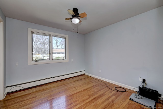 empty room featuring baseboard heating, wood finished floors, ceiling fan, and baseboards