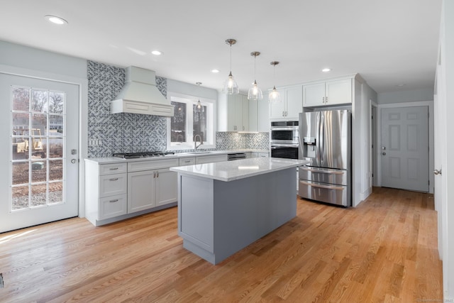 kitchen with custom exhaust hood, a sink, stainless steel appliances, light countertops, and white cabinetry