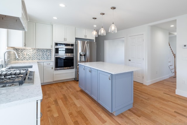 kitchen with white cabinets, light wood-style flooring, appliances with stainless steel finishes, and a sink