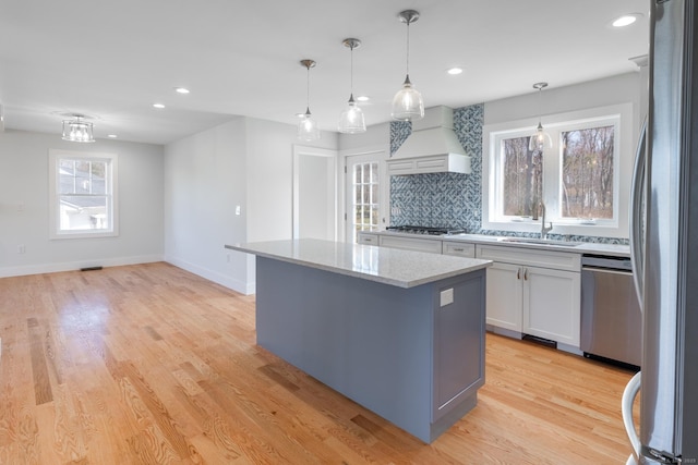 kitchen featuring a center island, a sink, decorative backsplash, stainless steel appliances, and custom range hood