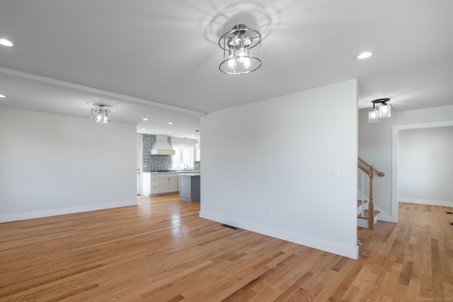 unfurnished living room with stairway, recessed lighting, and light wood-style flooring