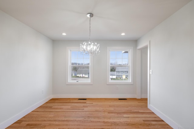 unfurnished dining area with light wood finished floors, baseboards, an inviting chandelier, and recessed lighting