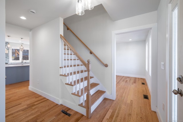 stairs featuring recessed lighting, wood finished floors, visible vents, and a notable chandelier