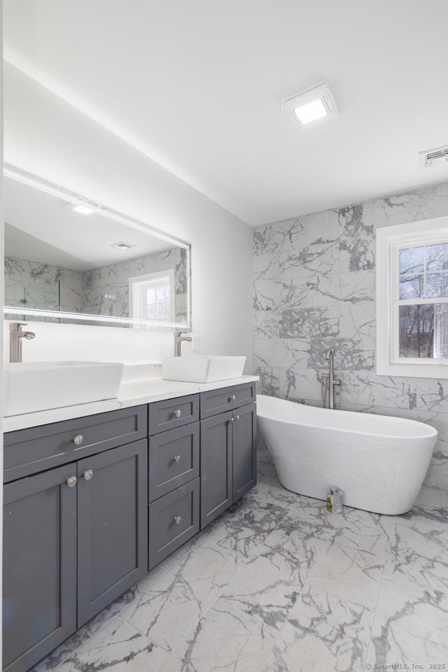 full bathroom with visible vents, marble finish floor, a sink, and double vanity