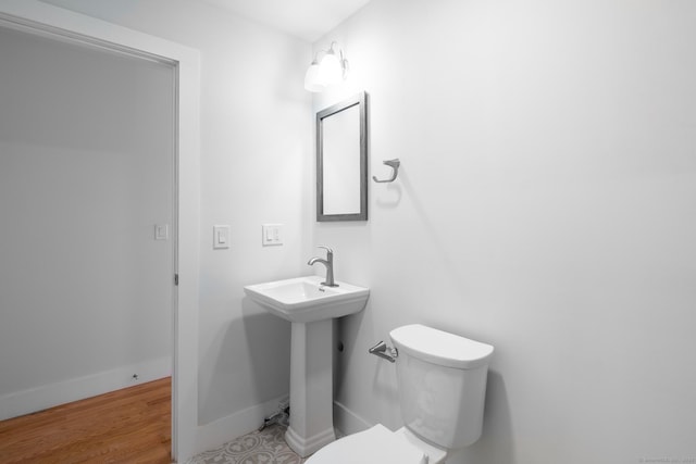 half bath with wood finished floors, toilet, and baseboards