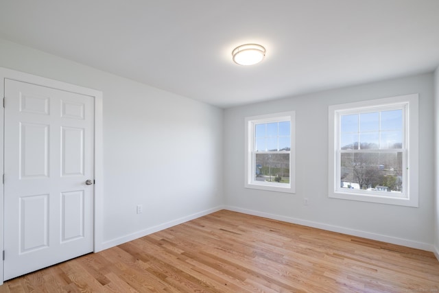 spare room featuring light wood finished floors and baseboards