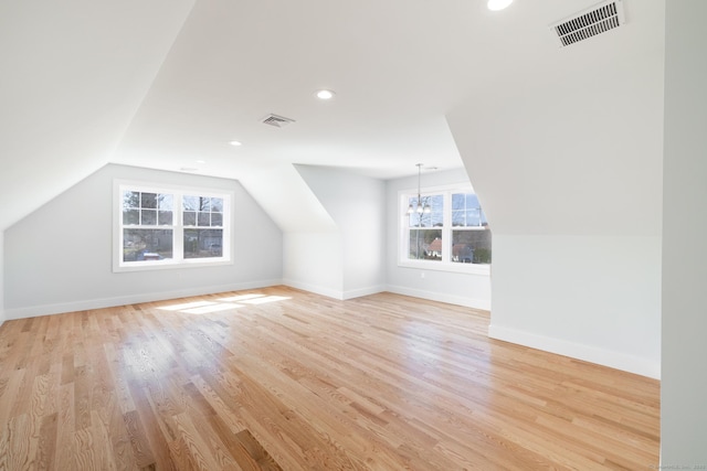 additional living space featuring lofted ceiling, visible vents, light wood-type flooring, and an inviting chandelier