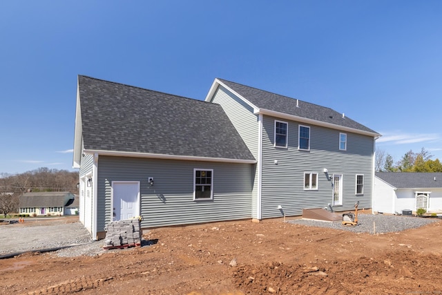 rear view of house featuring a shingled roof