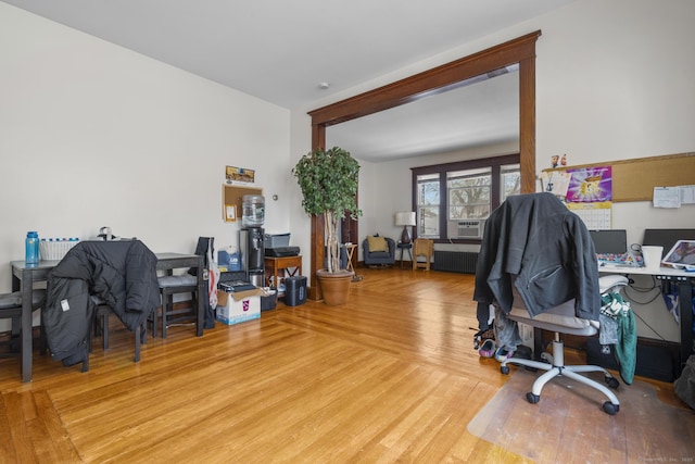 office space with radiator heating unit, wood finished floors, and cooling unit