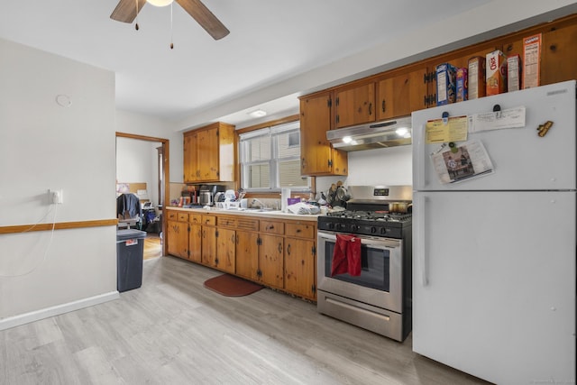 kitchen featuring stainless steel range with gas cooktop, freestanding refrigerator, light wood finished floors, and under cabinet range hood
