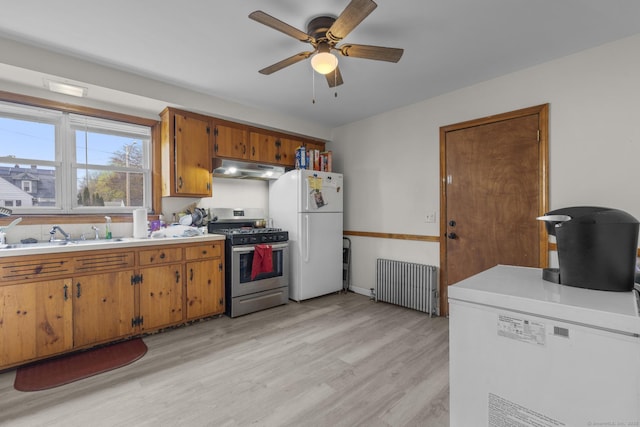 kitchen featuring ceiling fan, gas range, freestanding refrigerator, radiator, and under cabinet range hood