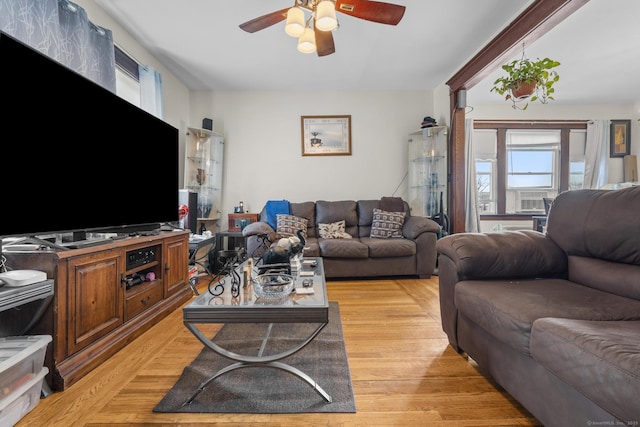 living area with cooling unit, a ceiling fan, and light wood-style flooring
