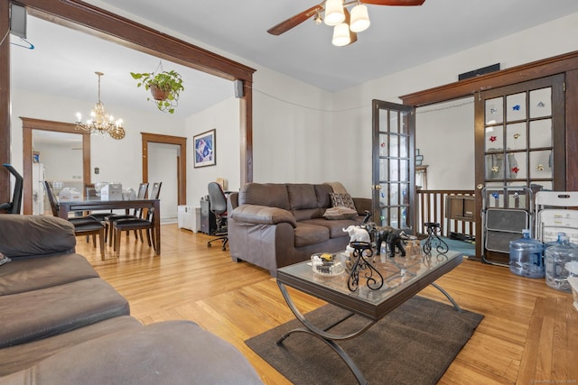 living area featuring wood finished floors and ceiling fan with notable chandelier