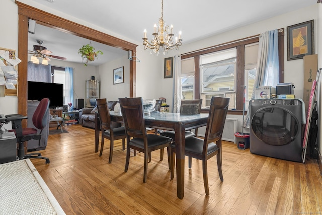 dining area with light wood-type flooring, washer / clothes dryer, and ceiling fan with notable chandelier