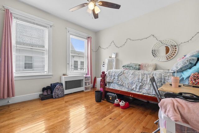 bedroom with wood-type flooring, radiator, ceiling fan, and baseboards