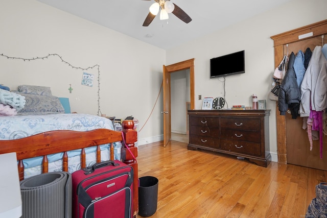 bedroom with a ceiling fan, baseboards, and light wood-type flooring