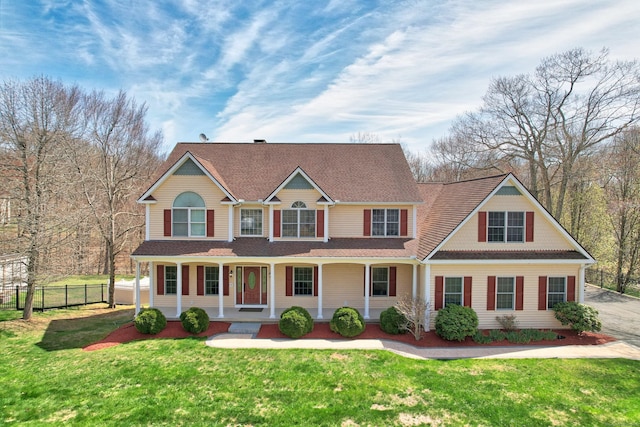 view of front of house featuring a shingled roof, a front yard, and fence