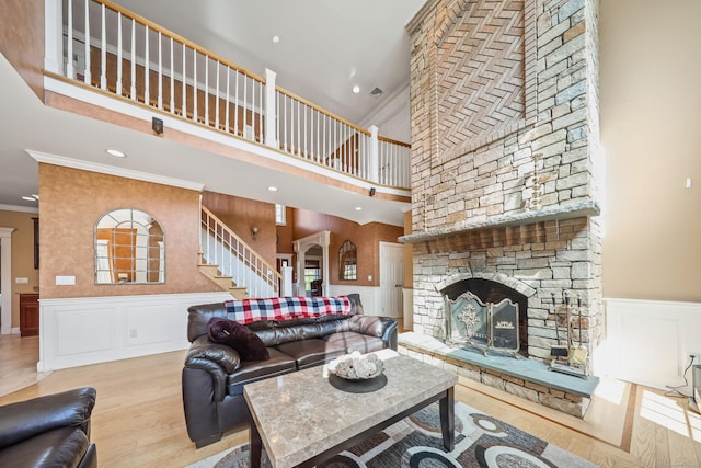 living room featuring wood finished floors, stairway, a decorative wall, a fireplace, and ornamental molding