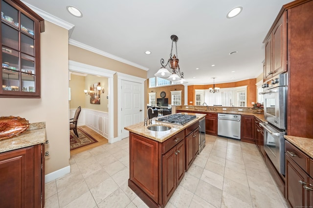 kitchen featuring a wainscoted wall, stainless steel appliances, a sink, light stone countertops, and pendant lighting