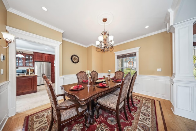 dining area with an inviting chandelier, a decorative wall, wainscoting, and decorative columns