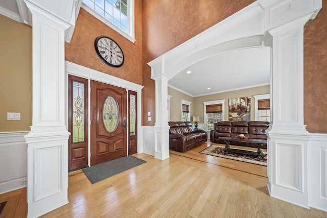 foyer entrance with plenty of natural light, light wood-style floors, and ornate columns