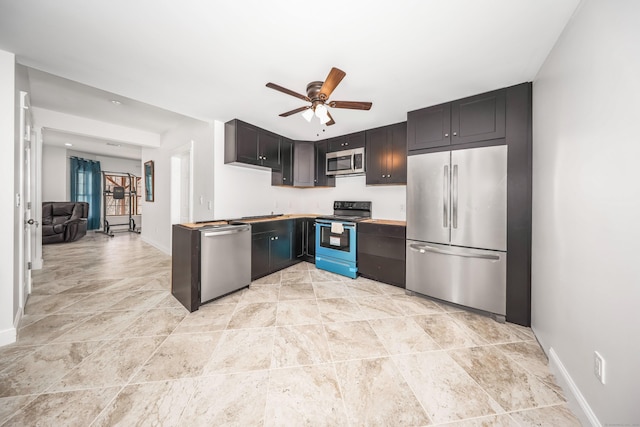 kitchen featuring stone finish floor, ceiling fan, baseboards, and stainless steel appliances