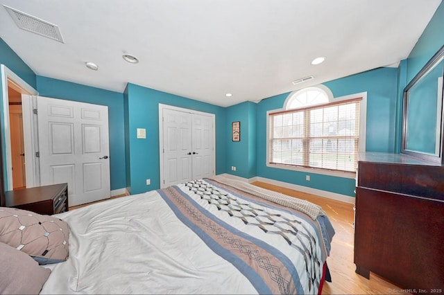 bedroom featuring a closet, visible vents, wood finished floors, and baseboards
