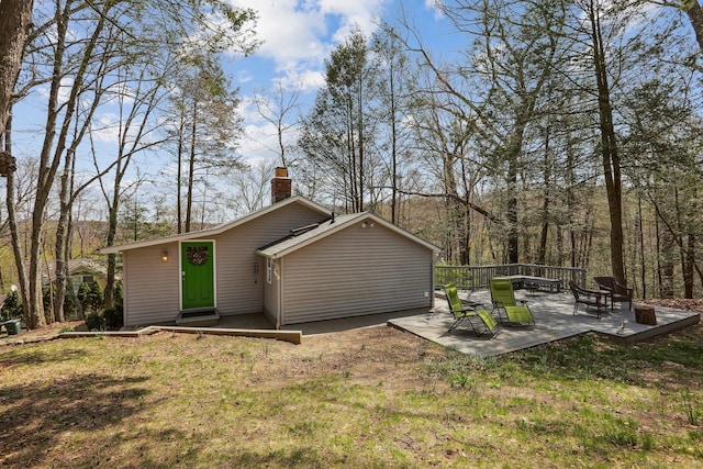 back of property featuring a chimney, a patio area, and a lawn