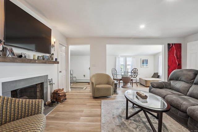 living room with light wood finished floors, baseboard heating, a fireplace, and recessed lighting