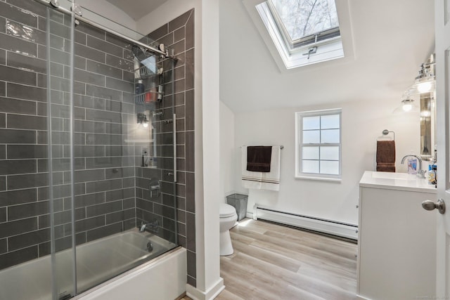 full bathroom featuring a baseboard heating unit, toilet, a skylight, combined bath / shower with glass door, and vanity