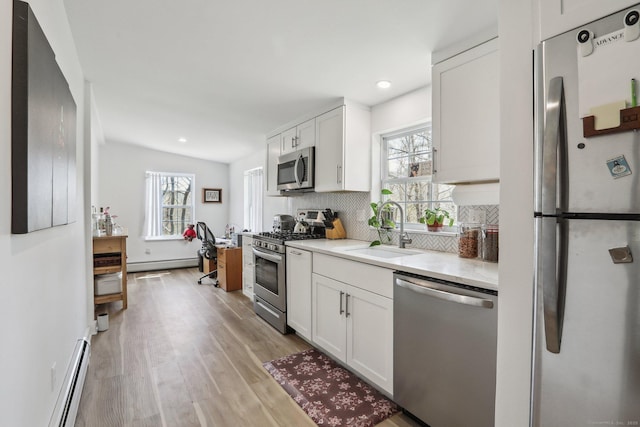 kitchen featuring plenty of natural light, a baseboard radiator, stainless steel appliances, and a sink