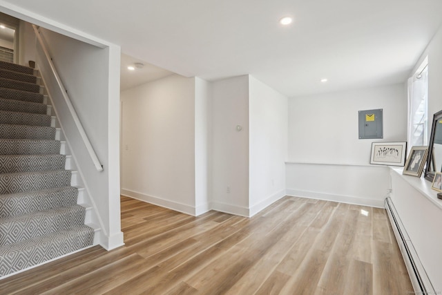 interior space with a baseboard heating unit, electric panel, baseboards, recessed lighting, and wood finished floors