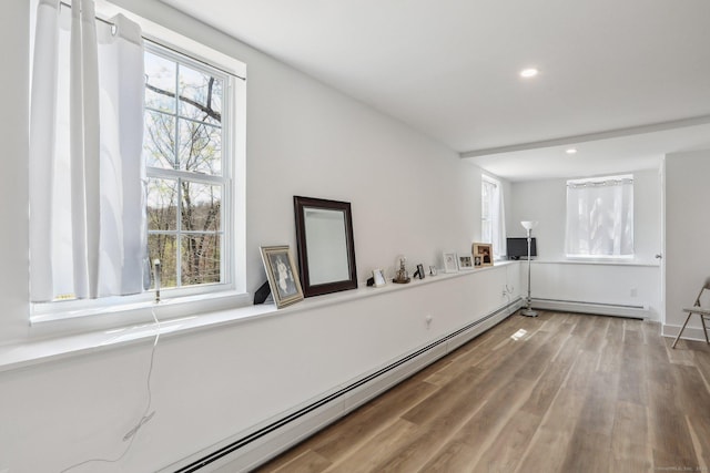 interior space with a baseboard heating unit, wood finished floors, recessed lighting, and a healthy amount of sunlight