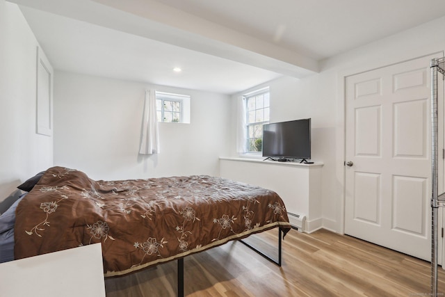 bedroom with a baseboard heating unit, wood finished floors, and recessed lighting