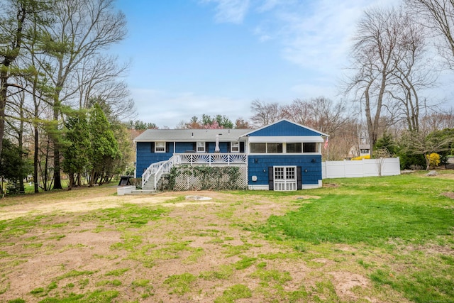rear view of property with fence, a deck, a lawn, and stairway