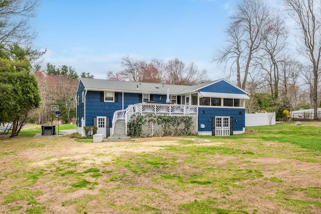 rear view of house featuring a lawn, fence, a wooden deck, and stairs