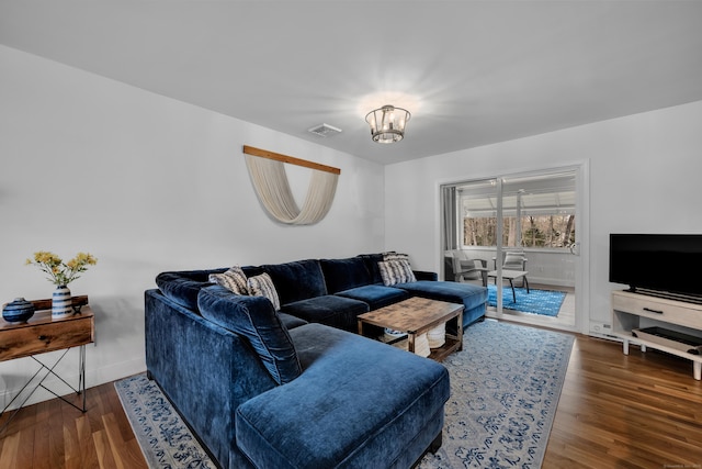 living area with visible vents, baseboards, wood finished floors, and a notable chandelier