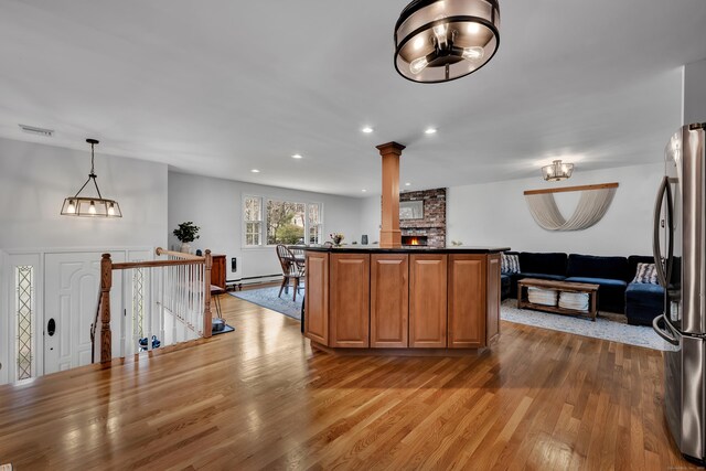 kitchen with dark countertops, baseboard heating, wood finished floors, freestanding refrigerator, and open floor plan