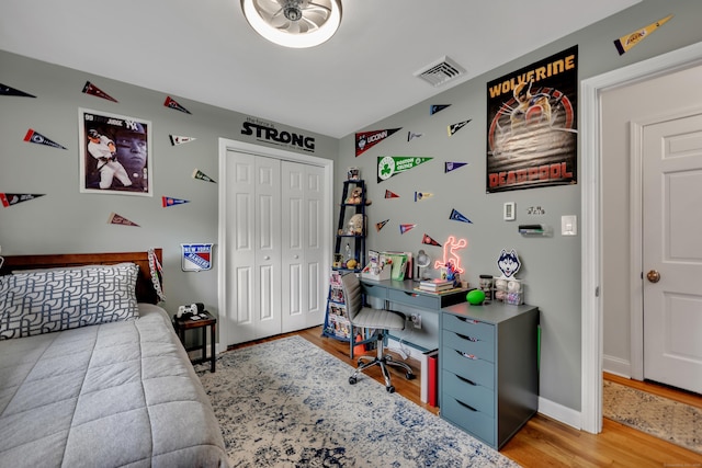 bedroom with visible vents, baseboards, wood finished floors, and a closet