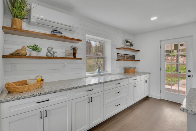 kitchen featuring open shelves, a wall mounted air conditioner, white cabinetry, light stone counters, and recessed lighting