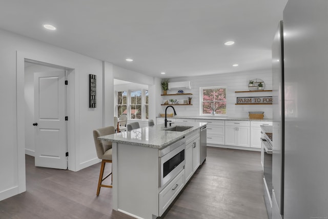 kitchen featuring stainless steel appliances, a sink, open shelves, dark wood-style flooring, and white cabinets