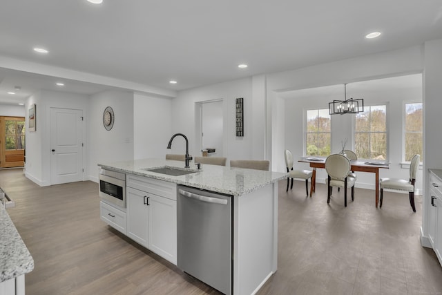 kitchen with dishwasher, a sink, wood finished floors, white cabinetry, and recessed lighting