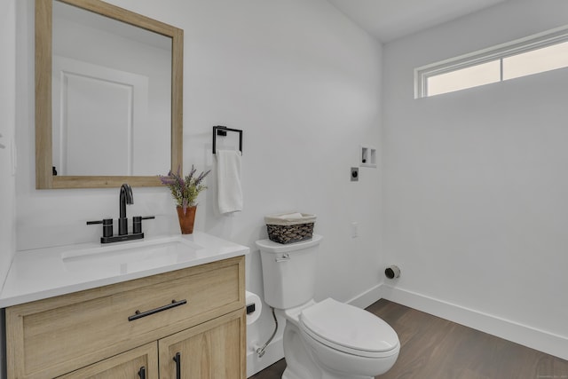 bathroom featuring baseboards, toilet, vanity, and wood finished floors
