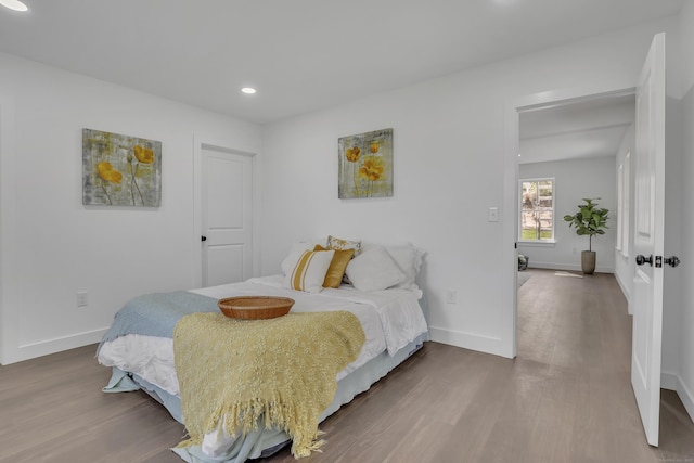 bedroom with wood finished floors, baseboards, and recessed lighting