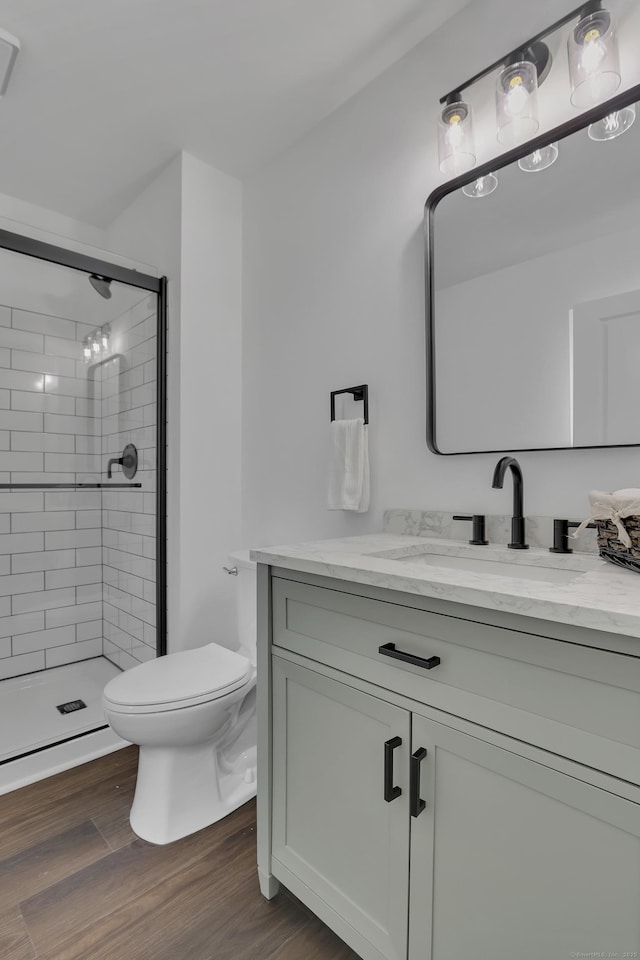 bathroom with toilet, wood finished floors, a shower stall, and vanity