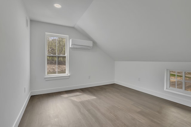 bonus room featuring a wall unit AC, vaulted ceiling, baseboards, and dark wood-style floors