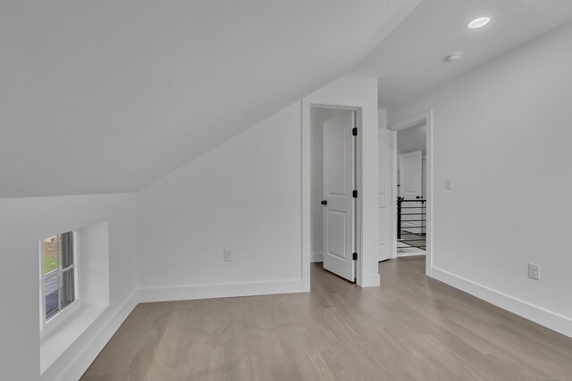 additional living space with vaulted ceiling, wood finished floors, and baseboards