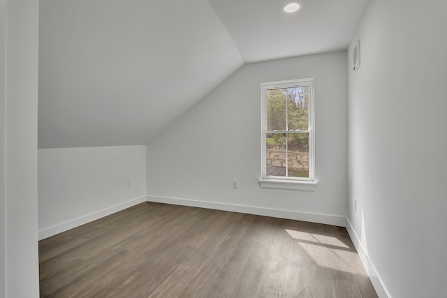 additional living space featuring vaulted ceiling, dark wood finished floors, and baseboards